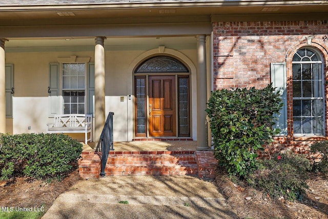 doorway to property featuring brick siding and a shingled roof