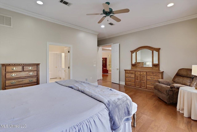 bedroom with wood finished floors, visible vents, and ornamental molding