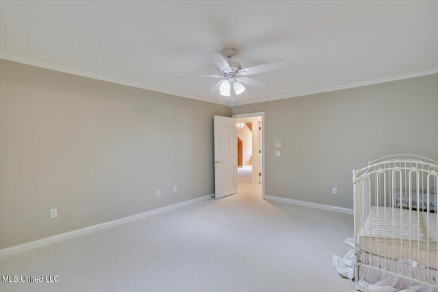 unfurnished bedroom with ornamental molding, a ceiling fan, baseboards, and carpet floors