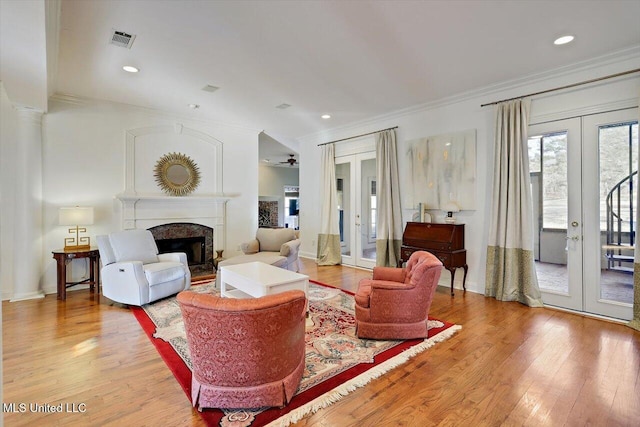 living area with light wood-type flooring, french doors, visible vents, and a premium fireplace