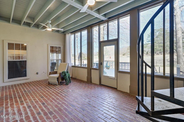 unfurnished sunroom featuring beamed ceiling and a ceiling fan