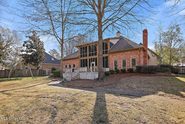 rear view of property featuring fence, a yard, a chimney, a deck, and brick siding