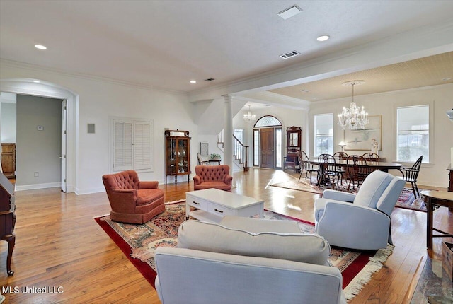 living area featuring visible vents, stairs, ornamental molding, light wood-style floors, and an inviting chandelier