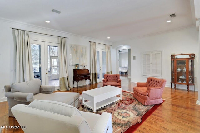 living room featuring visible vents, ornamental molding, french doors, wood finished floors, and arched walkways