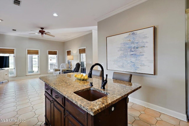 kitchen featuring crown molding, visible vents, dark brown cabinetry, and a sink