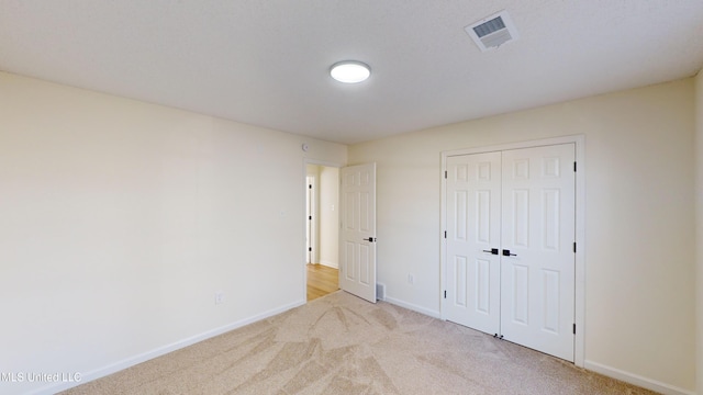 unfurnished bedroom featuring light carpet and a closet