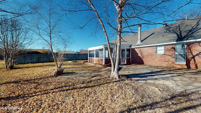 back of house with a sunroom and a lawn