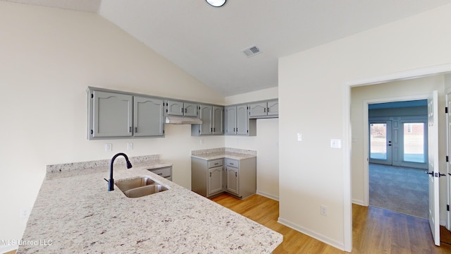 kitchen with hardwood / wood-style flooring, lofted ceiling, gray cabinets, and sink