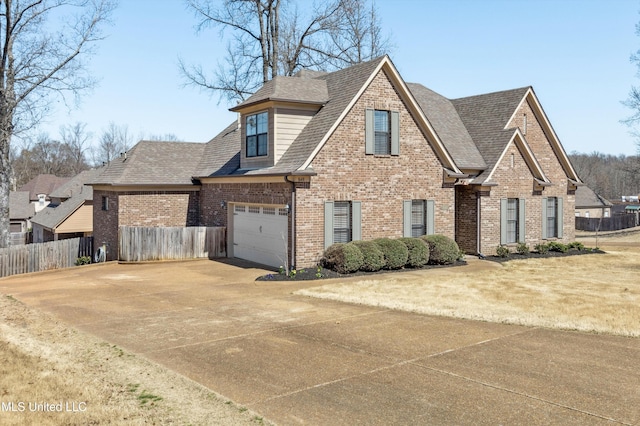 view of front facade featuring brick siding, driveway, a shingled roof, and fence