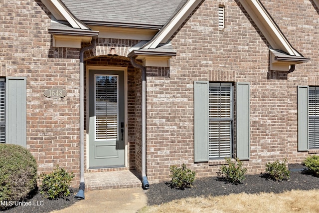 property entrance with brick siding and roof with shingles