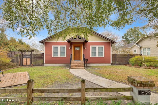 bungalow featuring a fenced front yard, a gate, and a front lawn