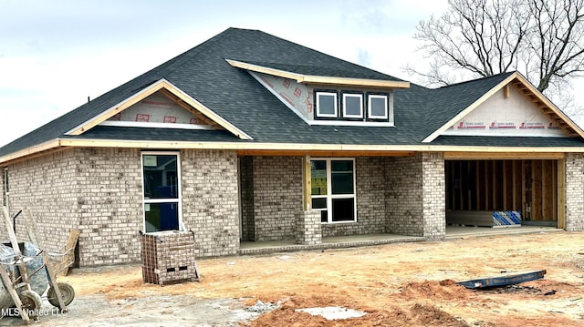 view of front of home featuring brick siding and a shingled roof