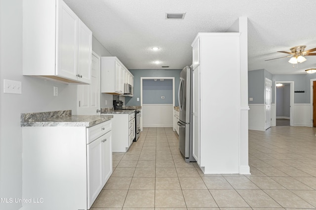 kitchen featuring visible vents, light tile patterned floors, appliances with stainless steel finishes, white cabinets, and a textured ceiling