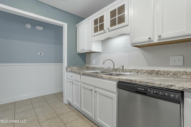kitchen with a sink, a textured ceiling, white cabinets, light tile patterned floors, and dishwasher