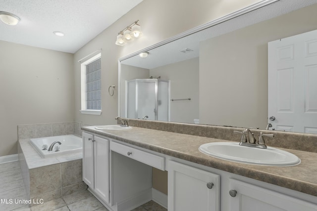 full bath with a sink, a garden tub, double vanity, and a textured ceiling