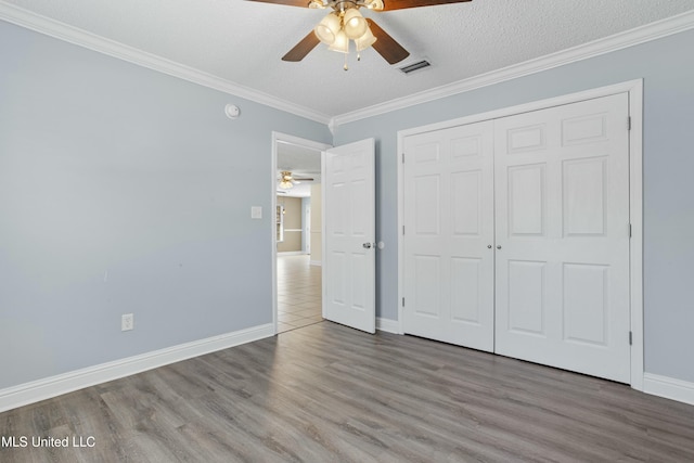 unfurnished bedroom featuring visible vents, ornamental molding, wood finished floors, a closet, and a textured ceiling