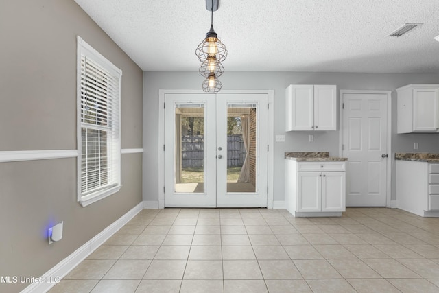 interior space with visible vents, a textured ceiling, french doors, light tile patterned floors, and baseboards
