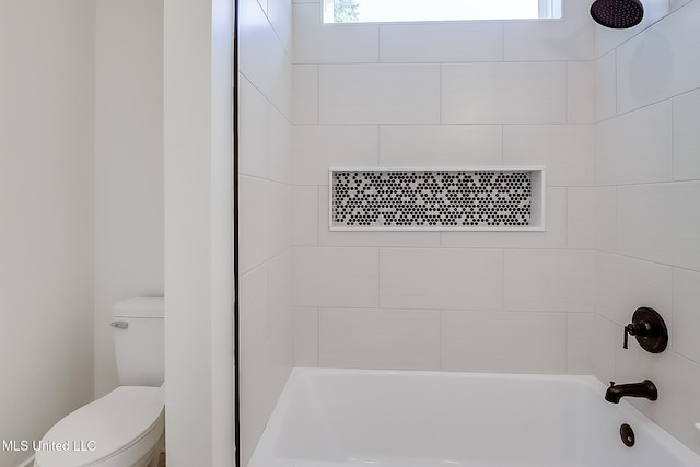 bathroom featuring tiled shower / bath combo and toilet