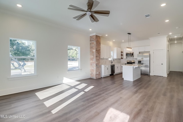 kitchen with appliances with stainless steel finishes, white cabinetry, a center island, wood-type flooring, and decorative light fixtures