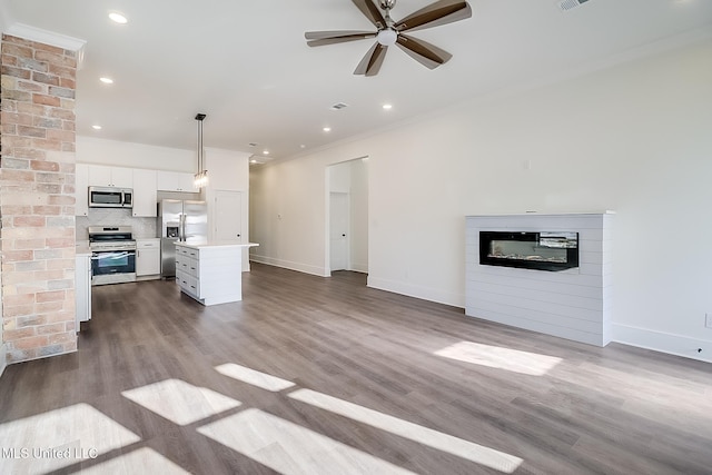 unfurnished living room featuring hardwood / wood-style floors, ornamental molding, a large fireplace, and ceiling fan