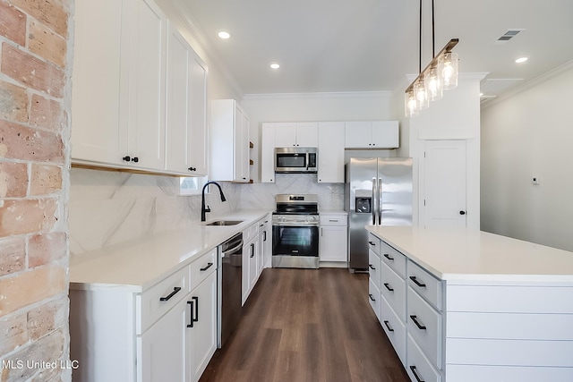 kitchen featuring pendant lighting, sink, appliances with stainless steel finishes, white cabinetry, and decorative backsplash