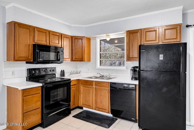 kitchen with decorative backsplash, brown cabinets, light countertops, black appliances, and a sink