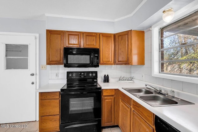 kitchen featuring brown cabinets, light countertops, a sink, and black appliances