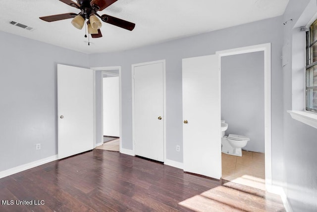 unfurnished bedroom featuring dark wood-type flooring, visible vents, baseboards, and ensuite bathroom