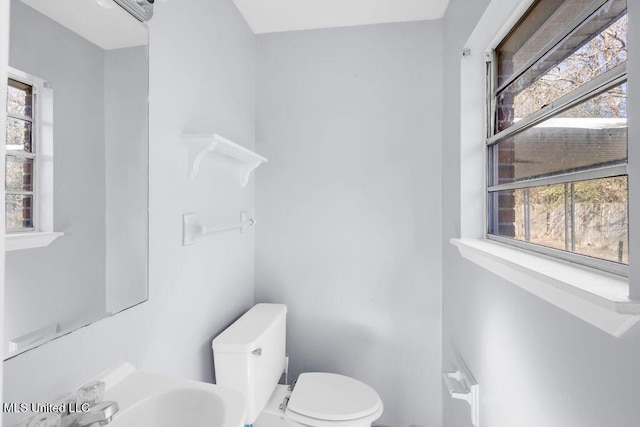 half bath featuring a sink, toilet, and a healthy amount of sunlight