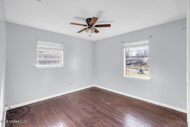 empty room featuring wood finished floors, a ceiling fan, and baseboards