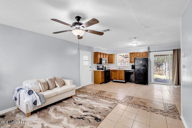 unfurnished living room featuring baseboards, visible vents, a ceiling fan, a textured ceiling, and light tile patterned flooring