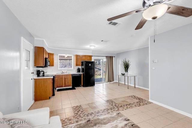 kitchen with brown cabinets, light countertops, black appliances, and light tile patterned floors