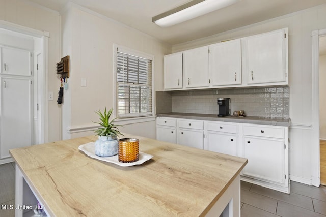 kitchen featuring tasteful backsplash, crown molding, and white cabinets