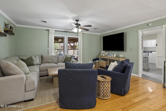 living room with washing machine and dryer, hardwood / wood-style floors, ceiling fan, and crown molding