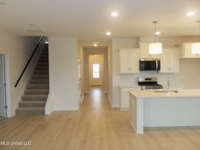 kitchen featuring sink, white cabinets, hanging light fixtures, range, and light hardwood / wood-style floors