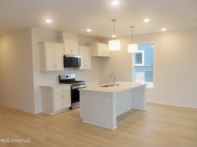 kitchen with an island with sink, stainless steel appliances, sink, and white cabinets