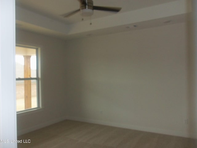 empty room featuring a raised ceiling and ceiling fan