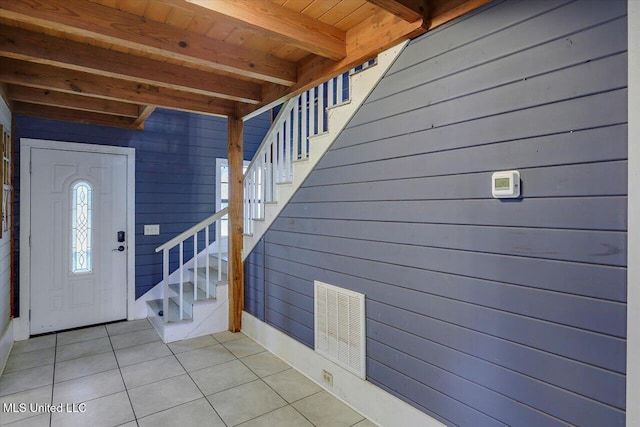 entryway featuring beamed ceiling, light tile patterned floors, wooden walls, and wooden ceiling