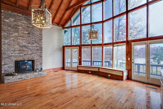 unfurnished living room with a wood stove, high vaulted ceiling, and a wealth of natural light