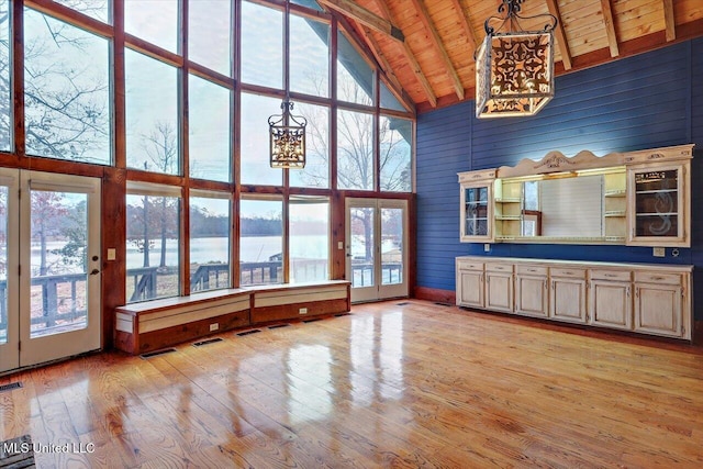 kitchen with a water view, light wood-type flooring, hanging light fixtures, and high vaulted ceiling