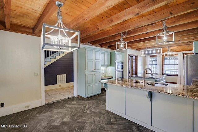 kitchen with stone countertops, decorative light fixtures, beam ceiling, and sink