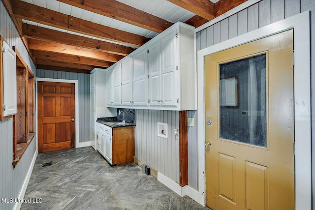 clothes washing area featuring dark parquet flooring, sink, cabinets, washer hookup, and wooden walls