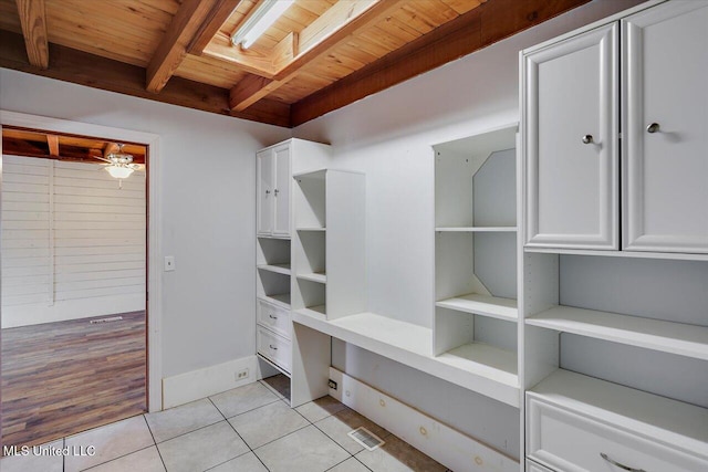 walk in closet with light tile patterned floors, a skylight, ceiling fan, and beam ceiling