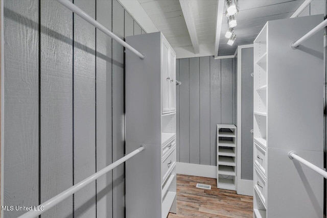 walk in closet with beam ceiling and hardwood / wood-style flooring