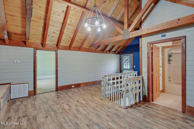 interior space with lofted ceiling with beams, light hardwood / wood-style floors, wood ceiling, and wood walls