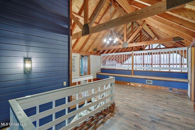 interior space with vaulted ceiling with beams, wood-type flooring, and wooden walls