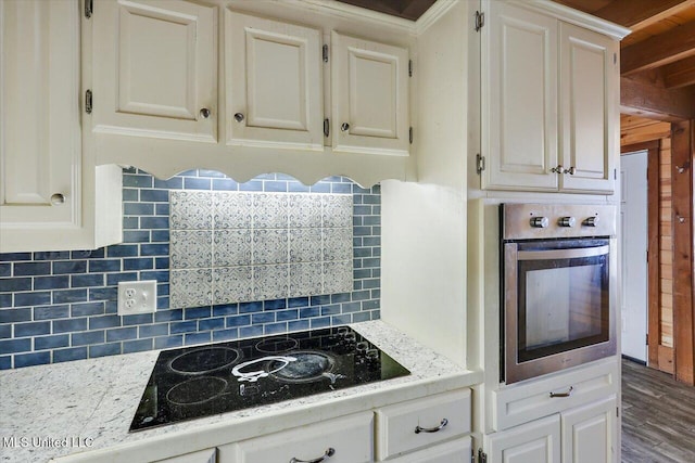 kitchen with white cabinetry, stainless steel oven, light stone counters, decorative backsplash, and black electric stovetop