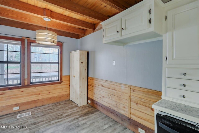 kitchen with beam ceiling, white cabinetry, light hardwood / wood-style flooring, decorative light fixtures, and wooden walls