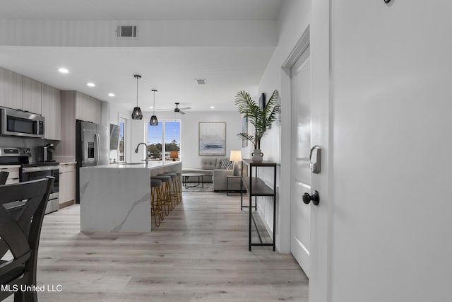 kitchen with stainless steel appliances, visible vents, light wood-style floors, open floor plan, and modern cabinets