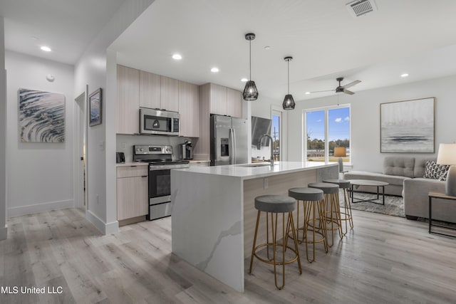 kitchen featuring a breakfast bar area, visible vents, appliances with stainless steel finishes, a sink, and modern cabinets